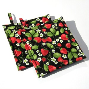 May include: Three black quilted pot holders with a strawberry print. The pot holders have a loop handle for easy grabbing.