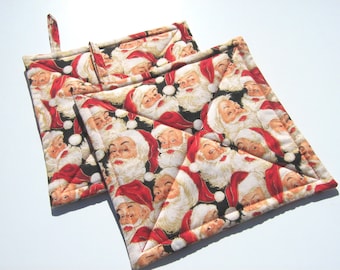 May include: Two black and white quilted pot holders with a repeating pattern of Santa Claus faces. The pot holders have red trim and a hanging loop.