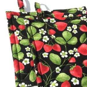 May include: Set of four black quilted pot holders with a strawberry and leaf design. The pot holders are red and green.
