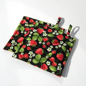 May include: Two black quilted pot holders with a strawberry print. The pot holders have a hanging loop.