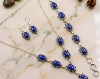 May include: A jewelry set featuring a silver necklace, a matching silver bracelet, and two silver drop earrings. Each piece is adorned with teardrop-shaped blue lapis lazuli stones set in intricate silver frames with a polished metallic finish.
