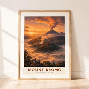 Könnte beinhalten: Ein gerahmter Kunstdruck mit einer Sonnenaufgangslandschaft des Mount Bromo in Indonesien. Die Szene zeigt Vulkangipfel über einem Wolkenmeer mit Rauchfahnen und Silhouetten von Menschen auf einem Grat. Der Text lautet MOUNT BROMO INDONESIA.