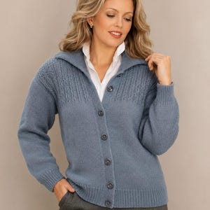 May include: A dusty blue knit cardigan featuring a collared neckline, long sleeves with ribbed cuffs, and a button-down front. The upper chest area displays a textured vertical ribbed pattern, while the lower body has a smooth knit finish.