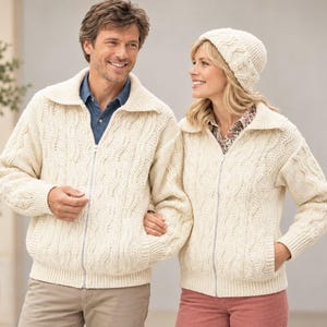 Peut inclure: Deux gilets zippés en tricot torsadé de couleur crème avec col et manches longues. Les gilets présentent un motif torsadé vertical texturé, des poignets côtelés et une fermeture éclair frontale. Un gilet est porté avec un pantalon beige, l'autre avec un pantalon rose.
