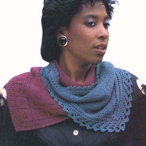 May include: A woman wearing a knitted shawl. The shawl is a combination of burgundy and blue, with a scalloped edge. The woman is wearing gold earrings and a dark jacket.