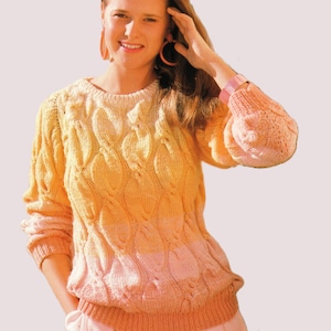 May include: A long-sleeved knit jumper featuring a cable knit pattern with a gradient colour transition from yellow at the top to a soft pink at the bottom. The jumper has a ribbed crew neckline, ribbed cuffs, and a ribbed hem in a solid peach tone.