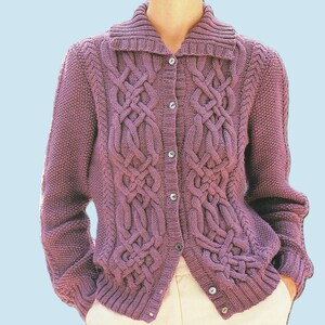 May include: A button-down, long-sleeved cardigan in a muted purple hue. The sweater features a textured cable knit design on the front panels and sleeves, with a ribbed collar and cuffs. The cardigan is shown over a pair of cream-colored pants.