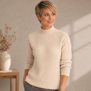 May include: A cream-colored, long-sleeved sweater featuring a ribbed knit texture and a mock neck collar. The garment has raglan sleeves and a straight hemline, providing a consistent vertical ribbed pattern throughout the entire body and sleeves.