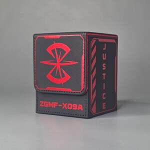Black and red trading card deck box with magnetic lid, textured exterior and bold justice themed design, premium tabletop card storage case