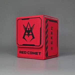 Angled Front view of red trading card deck box featuring Zaku II text panel and Red Comet text with faction style insignia design