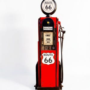 May include: A red and black Route 66 themed petrol pump cabinet featuring a circular top sign, a side-mounted fuel nozzle, and a glass-fronted display area containing small glasses. The display shows digital text reading This Sale 1.28, 8.53 Gallons, 1.49.