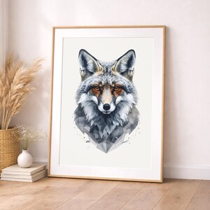 Könnte beinhalten: Gerahmter Aquarelldruck eines Fuchses. Der Fuchs hat ein grau-weißes Fell mit orangefarbenen Augen und einem geometrischen Design am unteren Rand. Der Rahmen ist helles Holz. Der Druck befindet sich an einer weißen Wand.