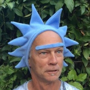 May include: A light blue, spiky hat with a matching eyebrow piece. The hat is made of a soft material and is worn by a person. The hat's design resembles a character from a popular animated series.