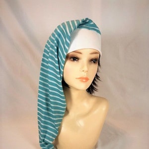 May include: A sleep cap with a white crown and a long, teal and white striped tail. The cap is displayed on a mannequin head. The cap's tail is tied with a white tassel.