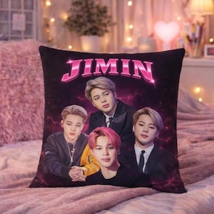 Könnte beinhalten: Schwarzes quadratisches Kissen mit dem Namen "JIMIN" in rosa, stilisiertem Text. Das Kissen zeigt vier Bilder einer Person. Der Hintergrund ist ein dunkles Lila mit rosa Akzenten.