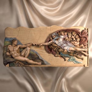 Op de afbeelding: Een rechthoekig houten wandreliëf dat de Schepping van Adam uitbeeldt. Het snijwerk toont een liggende figuur links die reikt naar een oudere figuur rechts omringd door cherubijnen, met geschilderde details in huidtinten en stoffen.