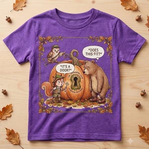 Könnte beinhalten: Ein violettes Kurzarm-T-Shirt mit einer grafischen Illustration eines Eichhörnchens, eines Bären und einer Eule um einen großen Kürbis mit Schlüsselloch. Der Text lautet: *IT'S A DOOR?*, *DOES THIS FIT?* und THE ENCHANTED LOCK PUMPKIN PATHWAY.