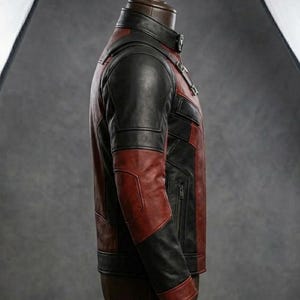 May include: A two-tone leather jacket in black and burgundy, displayed on a mannequin. The jacket features a stand-up collar, a zippered front, and paneling on the sleeves and torso. The jacket is a medium weight.