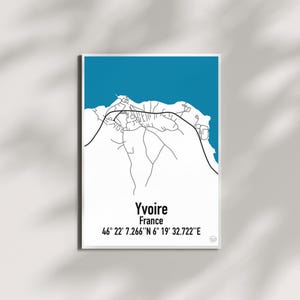 Peut inclure: Une affiche encadrée représentant une carte minimaliste d'Yvoire, France, avec une section supérieure bleu turquoise. La carte est dessinée en traits noirs sur fond blanc, avec le nom de la ville et ses coordonnées.