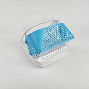 Puede incluir: Un dispositivo electrónico blanco y azul con una cubierta azul con patrón de panal. El dispositivo está abierto, revelando la pantalla y los botones. La cubierta es de un azul vibrante, contrastando con la base blanca.