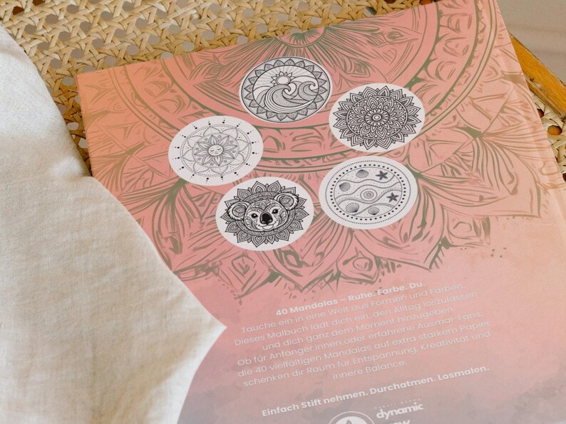 May include: A coloring book with a pink and beige mandala design. The cover features five circular illustrations of mandalas, including a koala, sun, and wave design. The text on the cover is in German.