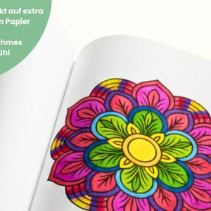 May include: A colorful mandala design on a white page. The mandala features a yellow center, surrounded by green, blue, pink, purple, and yellow petals. Text in the upper left corner reads, "Printed on extra strong paper for a pleasant painting experience."