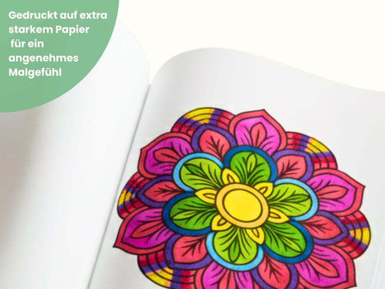 May include: A colorful mandala design on a white page. The mandala features a yellow center, surrounded by green, blue, pink, purple, and yellow petals. Text in the upper left corner reads, "Printed on extra strong paper for a pleasant painting experience."