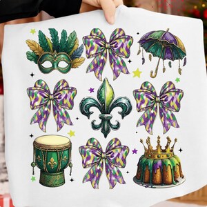 Könnte beinhalten: Ein weißer Stoff mit farbenfrohen Illustrationen von Mardi-Gras-Symbolen. Das Design umfasst eine grüne und goldene Maske mit Federn, Schleifen in Lila, Grün und Gold, eine Fleur-de-Lis, eine Trommel, einen Regenschirm und einen Königskuchen mit einer Krone.