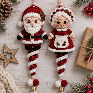Può includere: Due decorazioni all'uncinetto che raffigurano Babbo Natale e la Signora Natale. Ogni figura ha un corpo a spirale rosso e bianco, un campanellino dorato e un ciondolo a forma di fiocco di neve bianco alla base. Babbo Natale indossa un cappello.