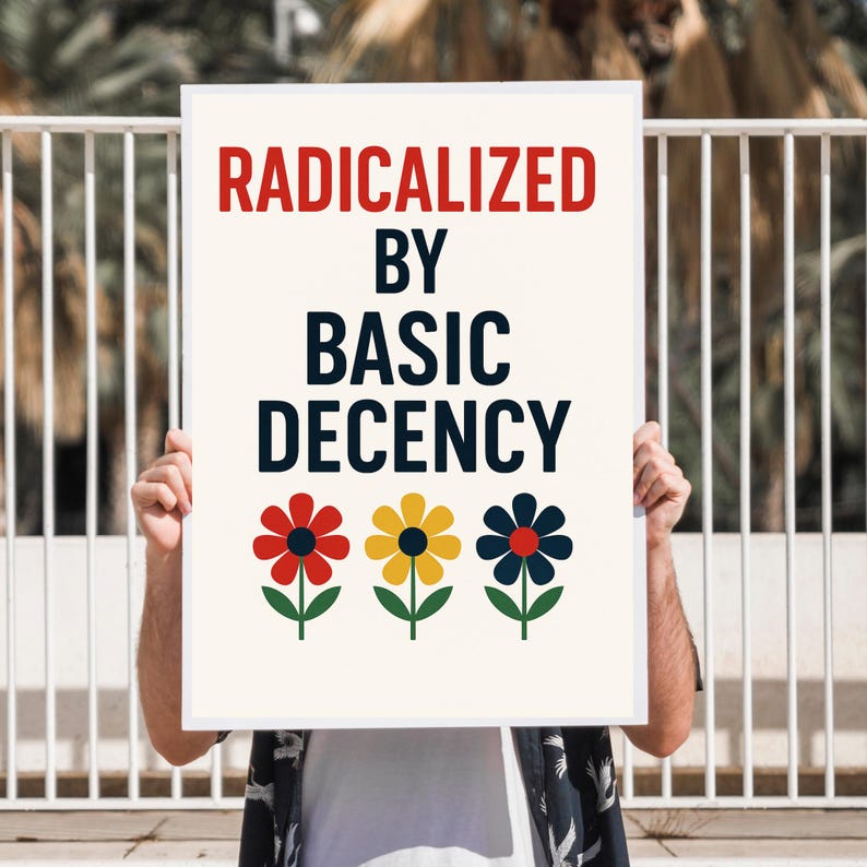 Peut inclure: Une affiche rectangulaire avec le texte "RADICALIZED BY BASIC DECENCY" en rouge et noir. En dessous, trois fleurs stylis&eacute;es rouges, jaunes et bleues avec des tiges et des feuilles vertes. L'affiche est tenue par une personne.