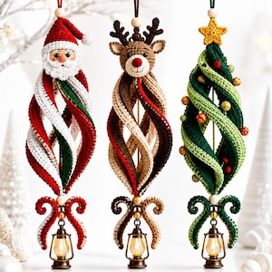 Könnte beinhalten: Drei hängende Häkelornamente in Form eines Weihnachtsmanns, eines Rentiers und eines Weihnachtsbaums. Jedes Ornament hat einen spiralförmigen Stoffkörper, eine Holzperle oben und eine kleine bronzefarbene Laterne an der Unterseite.
