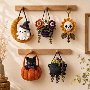 May include: Five crocheted Halloween decorations hanging on wooden wall racks. Items include a ghost on a yellow crescent moon, a potted plant with three eyeball flowers, a sunflower with a skull center, a black cat in a pumpkin, and a cauldron.