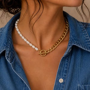 May include: A necklace featuring a half-and-half design with one side composed of round white pearls and the other side made of gold-toned metal chain links. The two sections are connected by a central gold-toned metal toggle clasp closure.