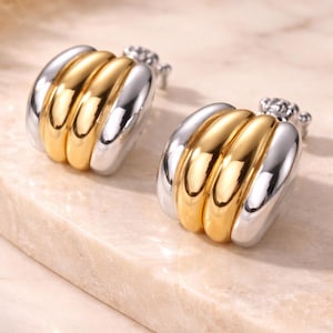 May include: A set of three ceramic mugs with a speckled, matte finish. The mugs are in shades of cream, light gray, and dark gray. Each mug has a simple, minimalist design, perfect for coffee or tea.