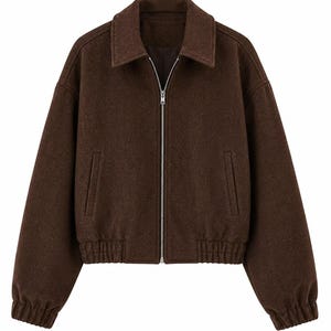 May include: A brown jacket with a collar and a silver zipper. The jacket has two front pockets and ribbed cuffs and hem. The jacket is made of a soft, textured material.