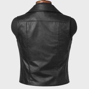 May include: A black leather vest displayed on a mannequin. The vest has a classic collar, a tailored fit, and vertical seams running down the front and back. The vest is a solid black color and appears to be made of smooth leather.