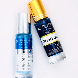 May include: Two perfume bottles with blue liquid and silver and gold caps are displayed on a white surface. One bottle has the text "D&G is blue" and the other says "Good Girl" and "12 ml". The bottles are from the "Have a Scent Collection".