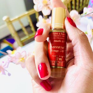 May include: A small perfume bottle with a gold cap and a red label is held in a hand with red nail polish. The label reads "Baccarat Rouge 540" and "12 ml". The bottle is part of the "Have a Scent Collection".