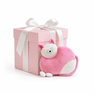 May include: A plush cat toy with a white face and pink body, positioned in front of a square pink gift box featuring a white polka dot pattern and a large white satin ribbon tied in a bow on top, creating a soft and decorative presentation.