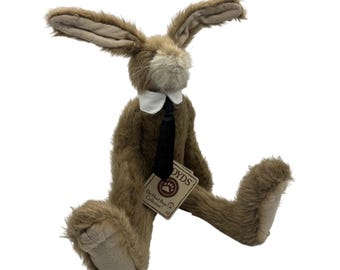 May include: A brown plush rabbit with long ears, wearing a white collar and a black necktie. The stuffed animal has a light tan muzzle and foot pads, and a cardboard tag attached to the neck reads The Head Bean Collection BOYDS.