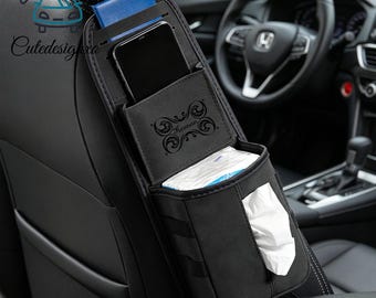 Può includere: Organizzatore per sedile auto nero con più scomparti per riporre oggetti. Dispone di una tasca per telefono, un erogatore di fazzoletti e un porta carte blu. La parola "Keenan" è stampata sull'organizzatore.