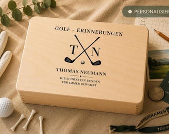 Può includere: Una scatola rettangolare in legno chiaro con un disegno stampato in nero di due mazze da golf incrociate, una pallina da golf, le iniziali T e N e il testo GOLF - ERINNERUNGEN, THOMAS NEUMANN e DIE SCHÖNSTEN RUNDEN FÜR IMMER BEWAHRT.