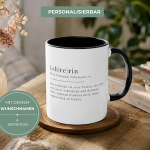 May include: A white ceramic mug with a black interior and handle, featuring a dictionary-style definition of the German word 'Lehrerin' printed in black text on the front, including the name 'Frau Neumann' and a descriptive sentence.