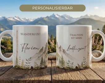 Può includere: Due tazze in ceramica bianca con un'illustrazione di un paesaggio montano con alberi e felci verdi alla base. La tazza sinistra riporta il testo "Wanderlust" e "Florian", mentre quella destra mostra "Draussen ist mein Lieblingsort."