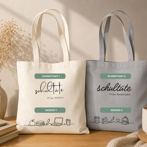 K&ouml;nnte beinhalten: Zwei Tragetaschen aus Canvas, eine cremefarbene und eine graue. Auf jeder Tasche steht das Wort "schult&uuml;te" in Schreibschrift, &uuml;ber einem gr&uuml;nen Rechteck mit "Design 1" oder "Design 2". Die cremefarbene Tasche hat eine Strichzeichnung von Schulmaterialien.