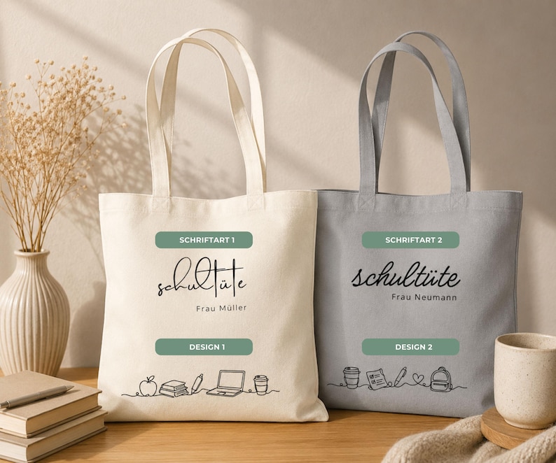 K&ouml;nnte beinhalten: Zwei Tragetaschen aus Canvas, eine cremefarbene und eine graue. Auf jeder Tasche steht das Wort "schult&uuml;te" in Schreibschrift, &uuml;ber einem gr&uuml;nen Rechteck mit "Design 1" oder "Design 2". Die cremefarbene Tasche hat eine Strichzeichnung von Schulmaterialien.