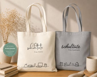 Può includere: Due borse di tela, una color crema e una grigia, con la scritta nera "Schultüte" e un nome sotto. La borsa color crema ha un disegno a tratto di materiale scolastico. La borsa grigia ha un design simile. Entrambe hanno manici lunghi.