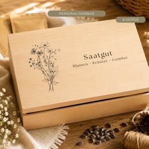 Könnte beinhalten: Eine rechteckige, helle Holzbox mit Klappdeckel, verziert mit einer schwarzen Strichzeichnung eines Wildblumenstraußes und dem Text "Saatgut Blumen · Kräuter · Gemüse". Die Box ist zur Aufbewahrung von Saatgut konzipiert und hat eine natürliche Maserung.