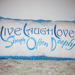 May include: A blue and white cushion with the text "Live Laugh Love Simply Often Deeply" embroidered in blue thread.