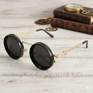 Puede incluir: Gafas de sol steampunk doradas con lentes redondas y oscuras y monturas negras ajustables. Las monturas tienen un diseño único con bisagras y puntas de patillas negras. Las gafas de sol están sobre un fondo de libros y engranajes vintage.